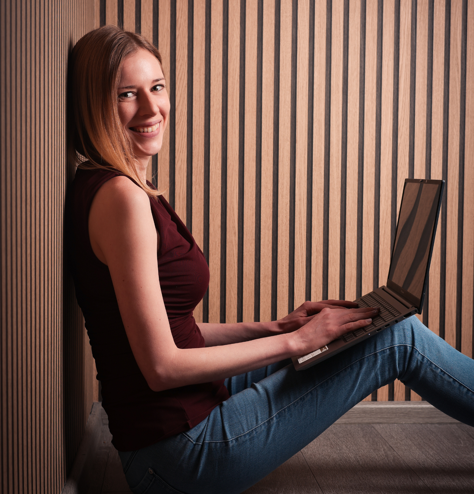 Helen mit Laptop Helen auf dem Boden sitzend mit Laptop und in die Kamera schauend